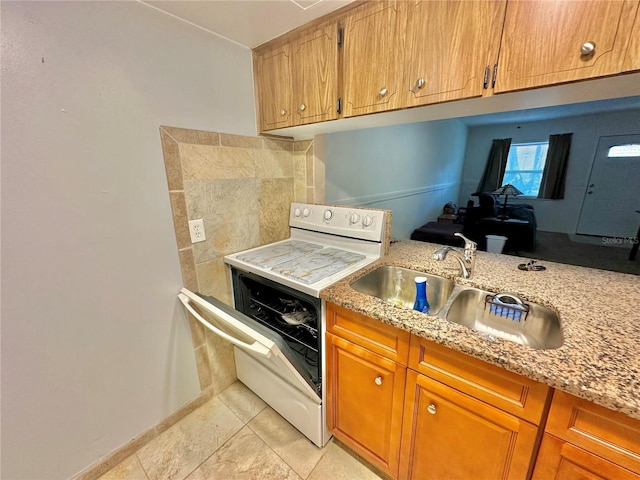 kitchen featuring a sink, brown cabinets, white electric range oven, and light stone countertops