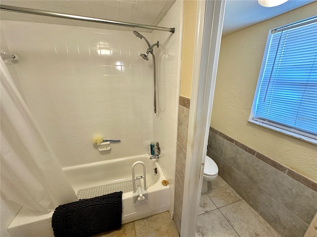 bathroom with tile patterned floors, toilet, tile walls, and shower / tub combo with curtain