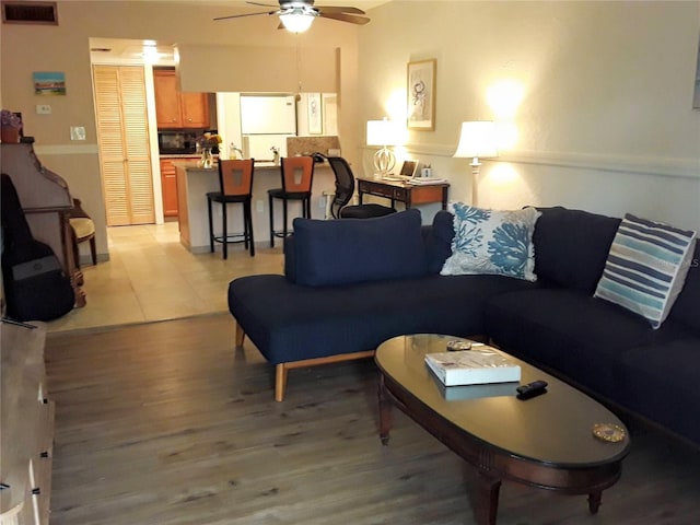 living room featuring visible vents, light wood finished floors, and ceiling fan