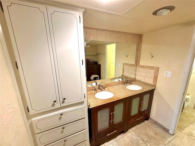 full bathroom with a sink, baseboards, tasteful backsplash, and double vanity