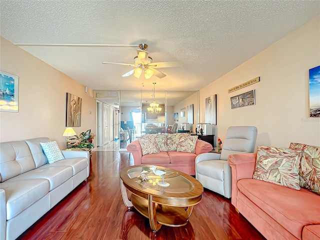 living room featuring ceiling fan with notable chandelier, a textured ceiling, and dark hardwood / wood-style flooring