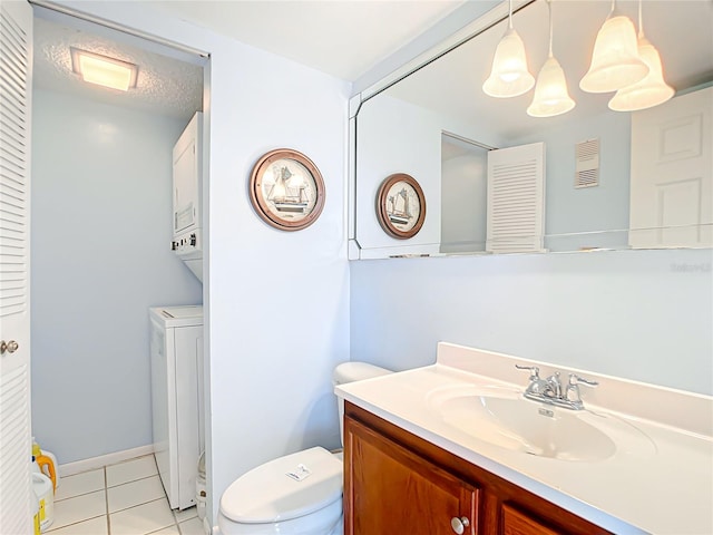 bathroom featuring tile floors, toilet, vanity, and stacked washing maching and dryer