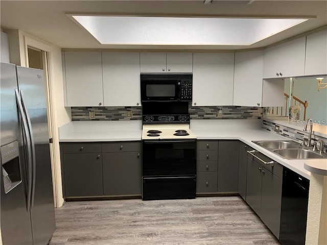 kitchen with tasteful backsplash, black appliances, sink, and gray cabinets