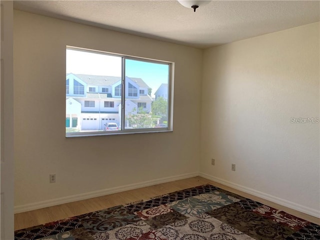 empty room with a textured ceiling and hardwood / wood-style flooring