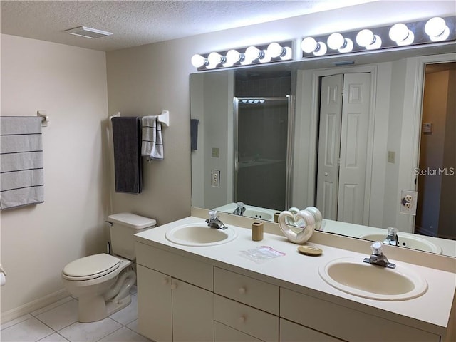 bathroom with toilet, large vanity, a textured ceiling, dual sinks, and tile floors