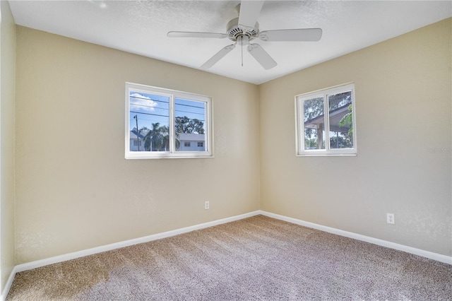 empty room with ceiling fan, plenty of natural light, and carpet