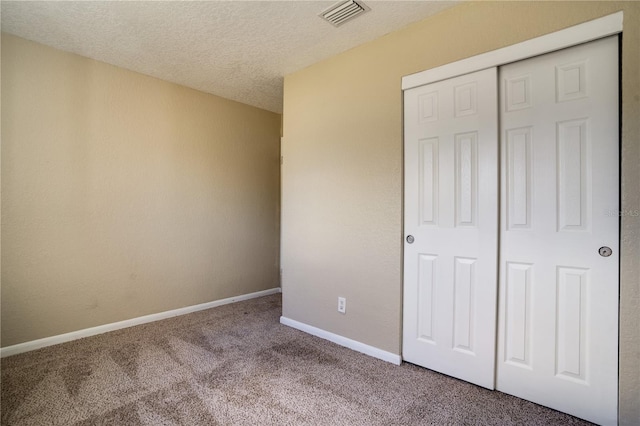 unfurnished bedroom with a textured ceiling, a closet, and carpet floors