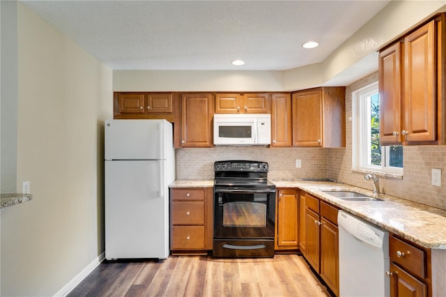 kitchen with white appliances, sink, light wood-type flooring, and decorative backsplash