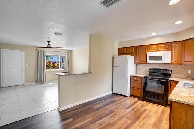 kitchen featuring tasteful backsplash, light stone counters, white appliances, ceiling fan, and light hardwood / wood-style flooring