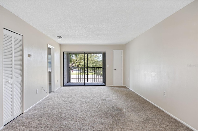 carpeted empty room with a textured ceiling