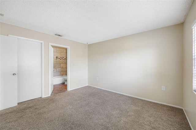 unfurnished bedroom with a textured ceiling, connected bathroom, and carpet floors