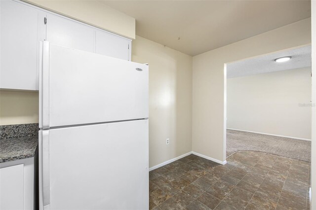 101 Lake Ave NE Unit 225, Largo, FL 33771 - kitchen featuring freestanding refrigerator, stone counters, white cabinetry, and baseboards