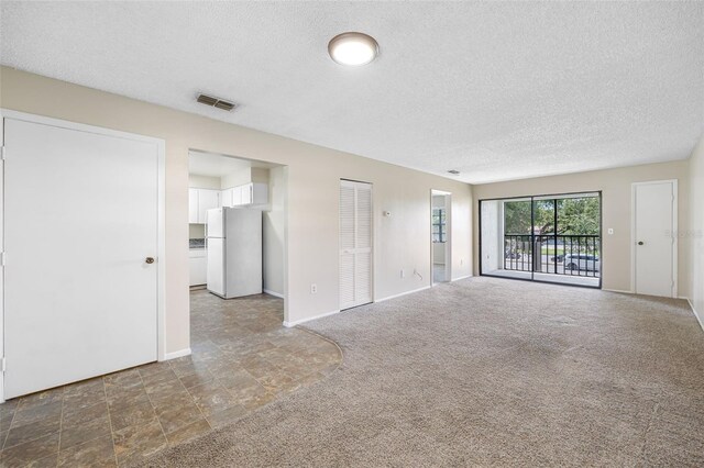 unfurnished living room featuring a textured ceiling and dark colored carpet