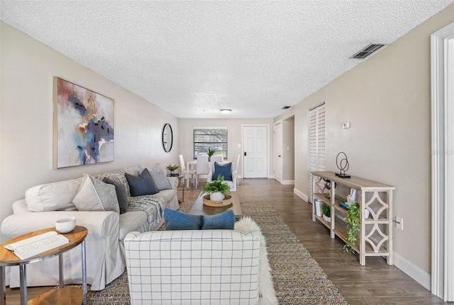 living room featuring dark wood-type flooring and a textured ceiling