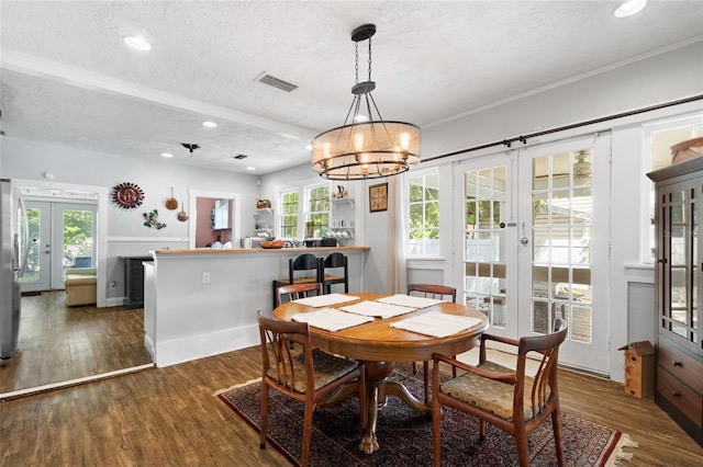 dining room with plenty of natural light, dark wood-type flooring, a textured ceiling, and french doors