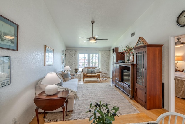 living room with ceiling fan, lofted ceiling, and light hardwood / wood-style floors