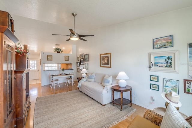 living room featuring light hardwood / wood-style floors, ceiling fan, and vaulted ceiling