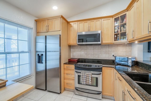 kitchen featuring light brown cabinets, lofted ceiling, light tile patterned flooring, and appliances with stainless steel finishes