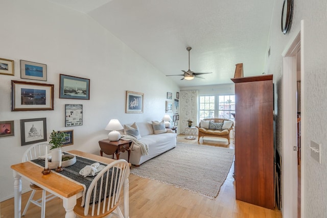 living room featuring ceiling fan, light wood-type flooring, and lofted ceiling