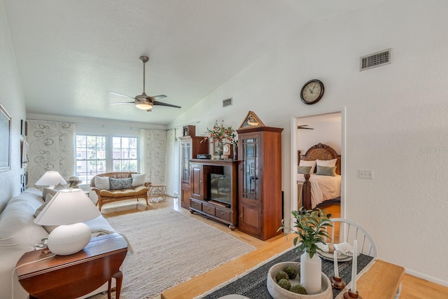 living room featuring light hardwood / wood-style floors, ceiling fan, and high vaulted ceiling