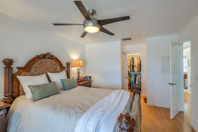 bedroom featuring a closet, light wood-type flooring, a spacious closet, and ceiling fan