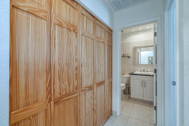 bathroom with toilet, vanity, and tile patterned floors