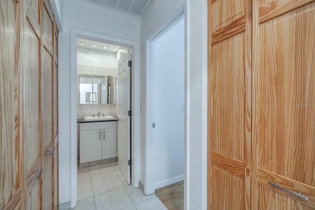 corridor featuring light tile patterned flooring and sink