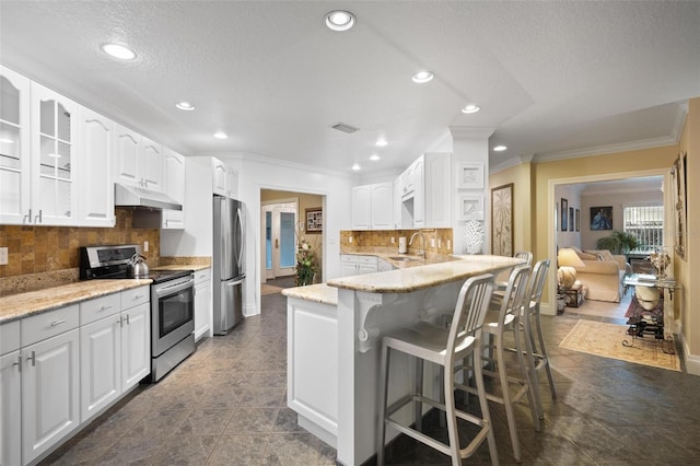 kitchen with tasteful backsplash, white cabinets, appliances with stainless steel finishes, and a breakfast bar area