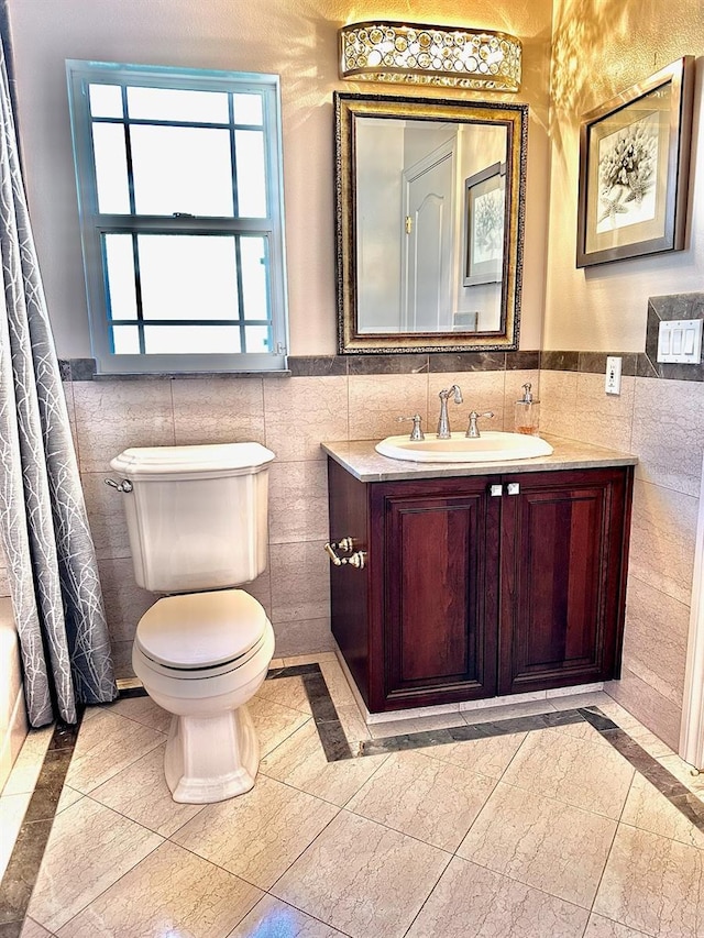 bathroom featuring toilet, vanity, and tile walls