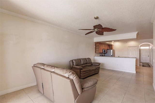 tiled living room with a textured ceiling, ceiling fan, and ornamental molding