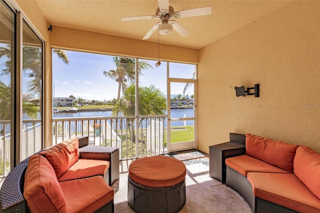 sunroom / solarium with a healthy amount of sunlight, ceiling fan, and a water view