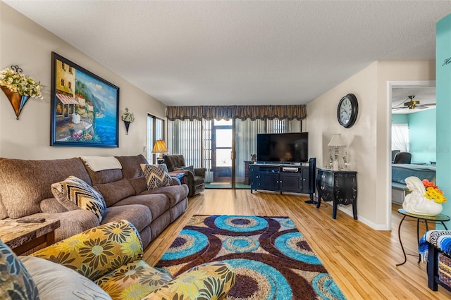 living room featuring light hardwood / wood-style floors, a textured ceiling, and ceiling fan