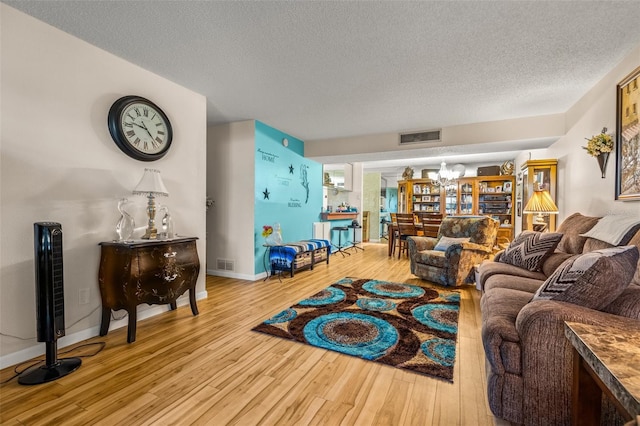 living room with an inviting chandelier, light hardwood / wood-style flooring, and a textured ceiling