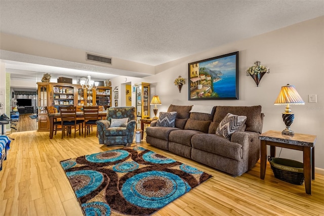 living room featuring a notable chandelier, hardwood / wood-style flooring, and a textured ceiling