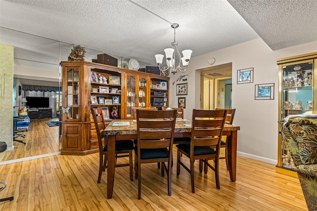 dining room with a chandelier, a textured ceiling, and light hardwood / wood-style flooring