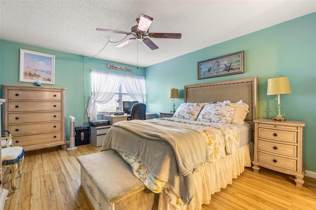 bedroom featuring ceiling fan, light hardwood / wood-style floors, and a textured ceiling