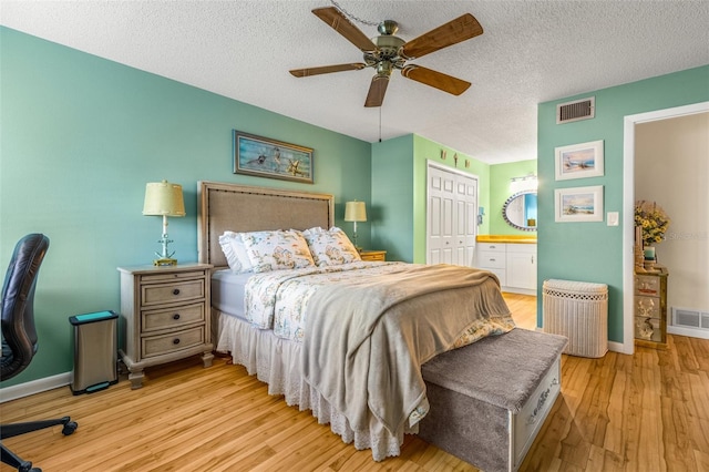 bedroom with a textured ceiling, a closet, ceiling fan, and light hardwood / wood-style flooring