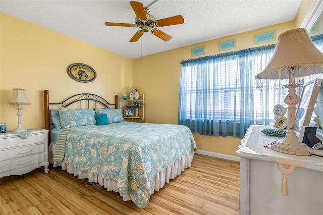 bedroom with a textured ceiling, light wood-type flooring, and ceiling fan