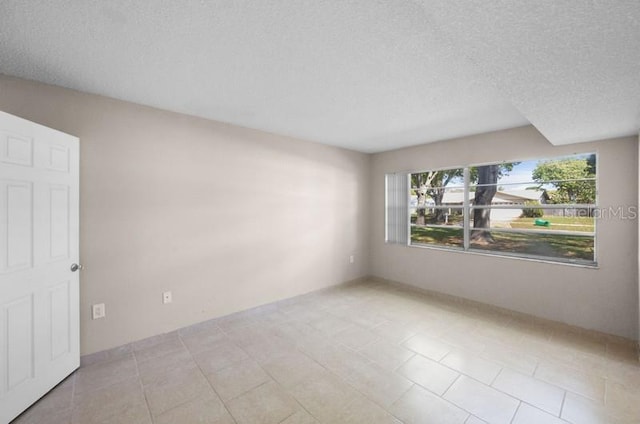 tiled empty room with a textured ceiling