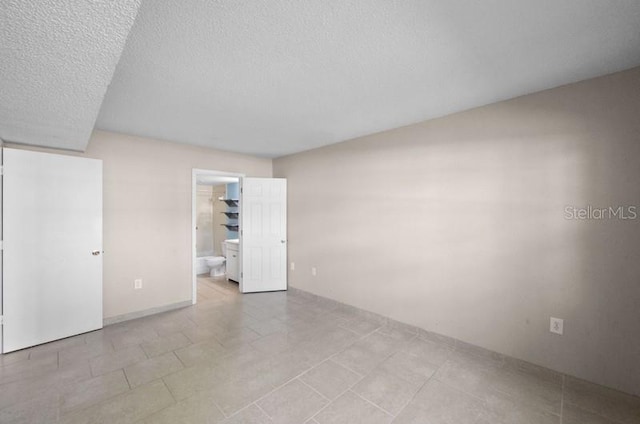 empty room featuring a textured ceiling and light tile flooring