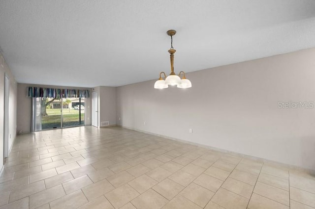 spare room with light tile flooring and a notable chandelier