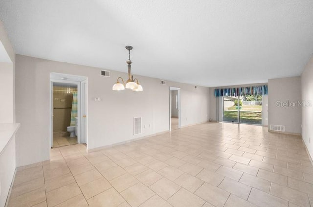 tiled spare room featuring a chandelier