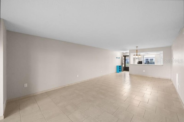 unfurnished living room with light tile flooring and a notable chandelier