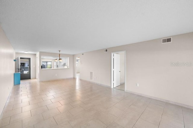 unfurnished living room with a textured ceiling, a chandelier, and light tile flooring