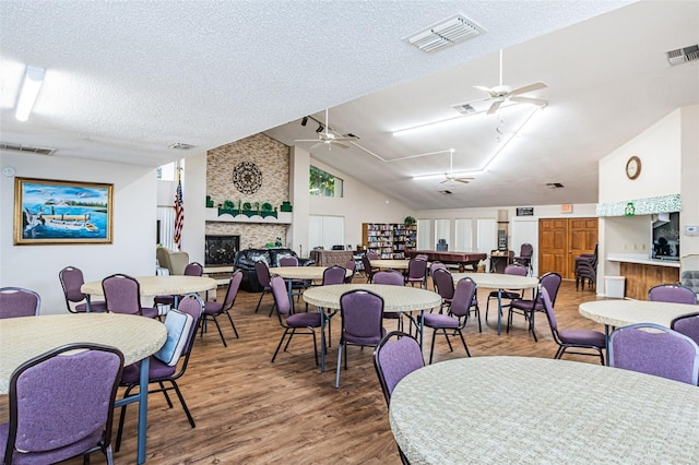 dining space with dark hardwood / wood-style flooring, ceiling fan, vaulted ceiling, and a textured ceiling