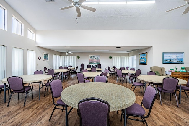 dining space with dark wood-type flooring, ceiling fan, and a textured ceiling