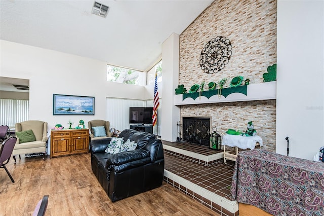 living room featuring a fireplace, high vaulted ceiling, and light hardwood / wood-style flooring