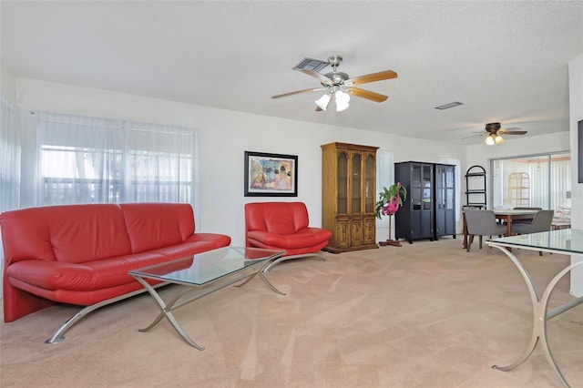 living room featuring a textured ceiling, ceiling fan, and light colored carpet