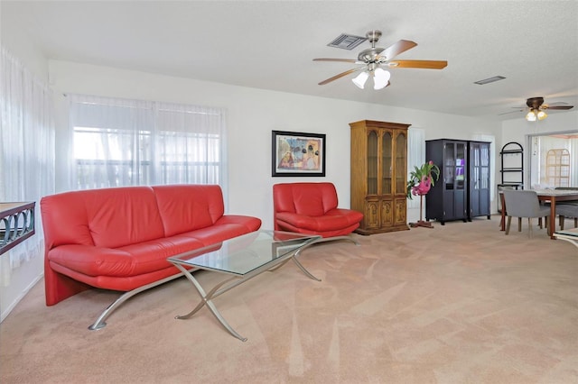 carpeted living room featuring ceiling fan and a textured ceiling