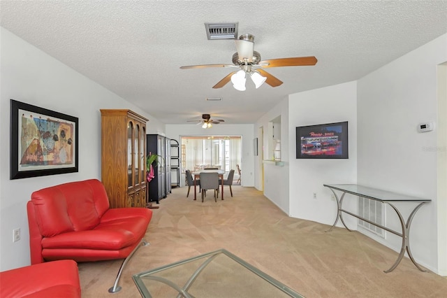 living room featuring light carpet, ceiling fan, and a textured ceiling